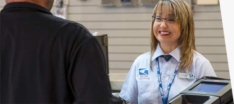 USPS retail associate selling products and services at the Post Office counter.